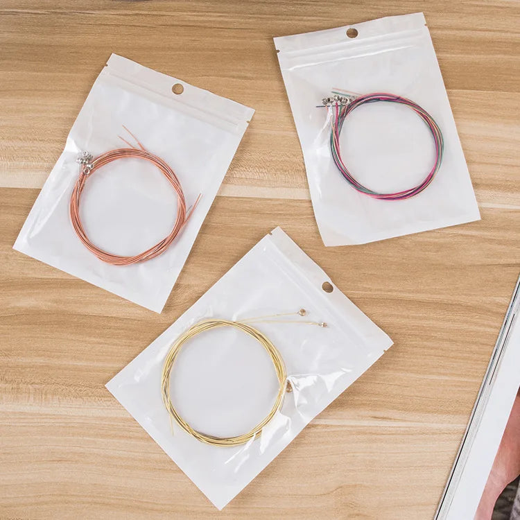 Guitar Strings in Packaging. One Gold Set, one bronze set, and one colorful set. | Sacred Tune